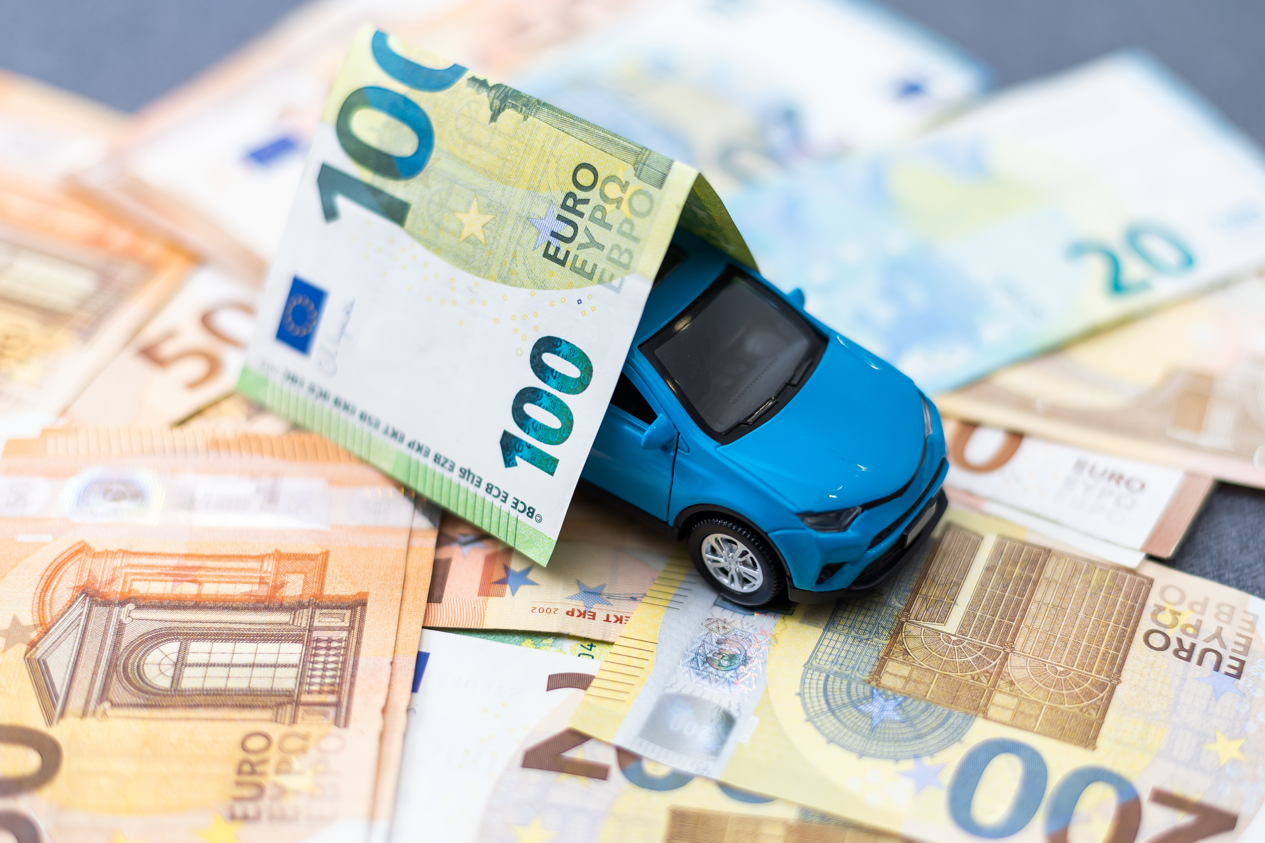 Miniatura di automobile su banconote in euro a rappresentare i costi e le scadenze del bollo auto Campania 2026, tra tasse regionali, pagamenti e gestione delle spese automobilistiche.